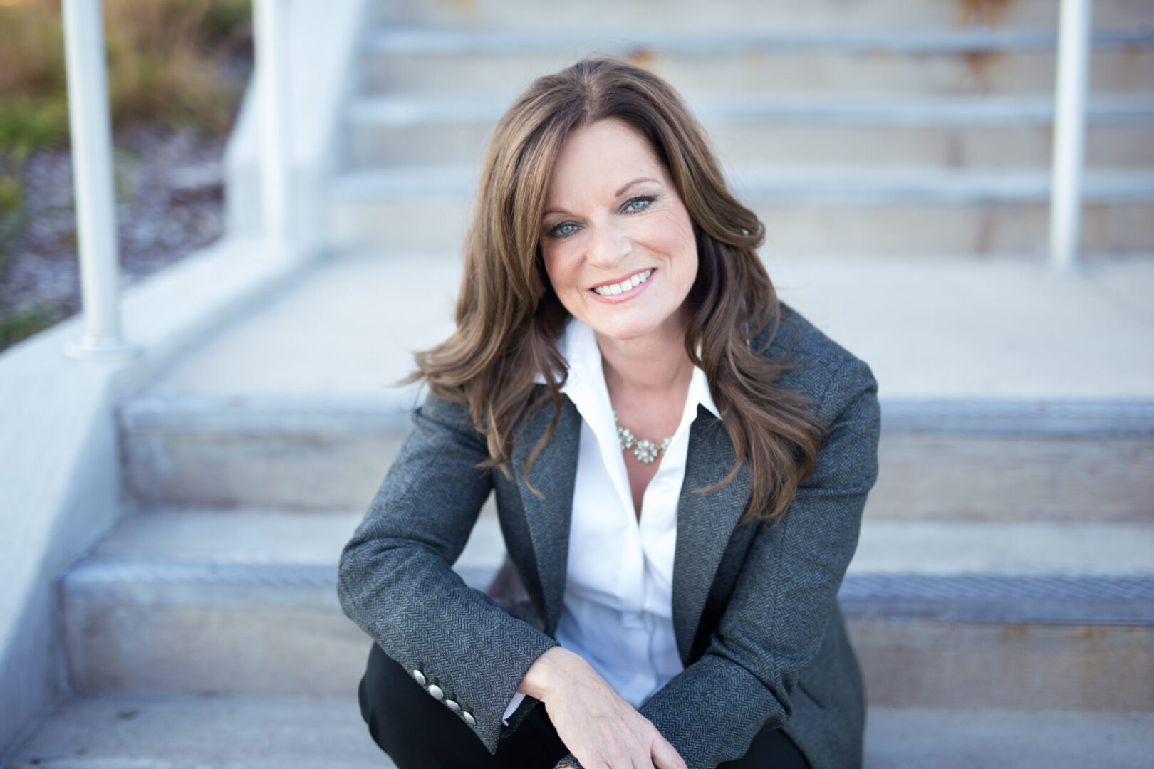 A woman sitting on some steps wearing a suit.